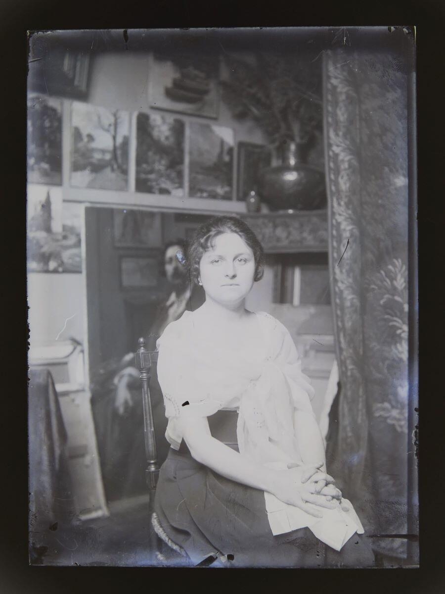 Portrait de jeune femme assise, les épaules entourées d'une étole brodée, posant dans l'atelier du peintre Léon Tirode
