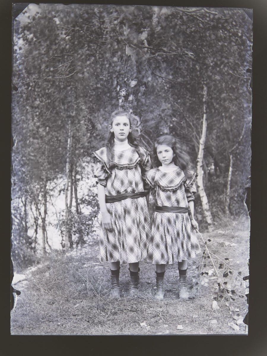 Deux fillettes en robes à tissu écossais posant dans la campagne