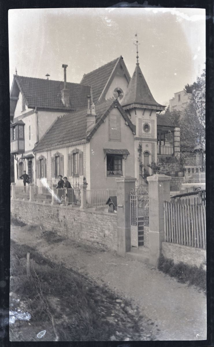 Un homme et deux femmes posant devant une villa
