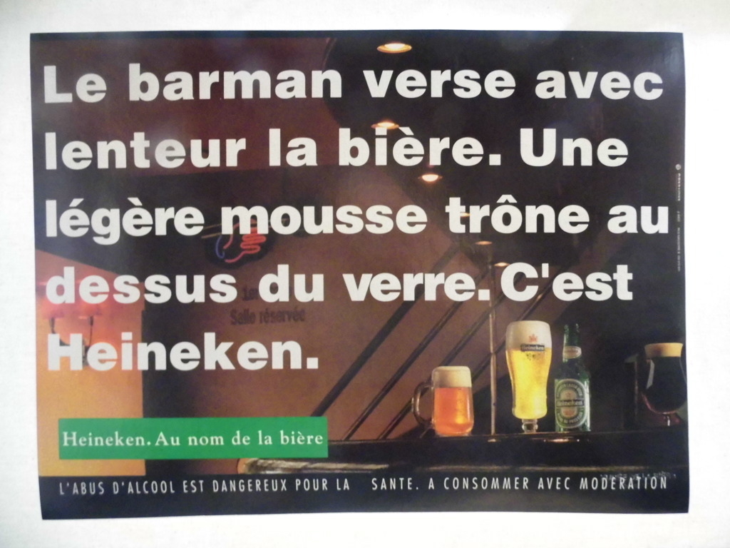 Le barman verse avec / lenteur la bière. Une / légère mousse trône au / dessus du verre. C'est / Heineken / Heineken. Au nom de la bière (titre inscrit)