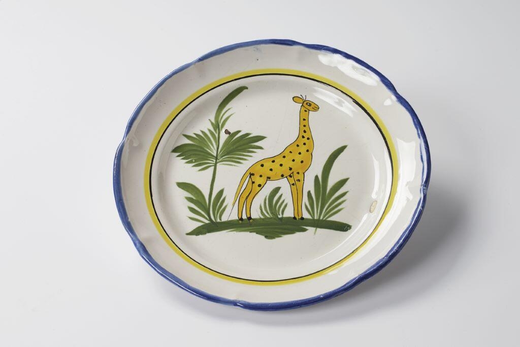 Assiette à la jeune girafe avec fougère à sa droite