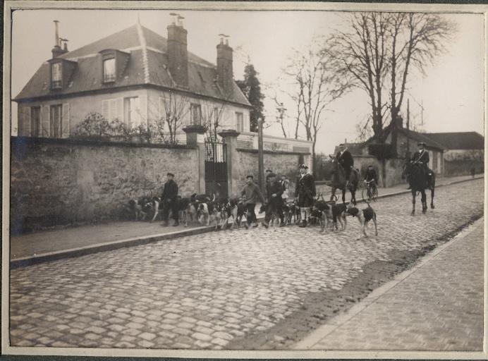 Photographie d'un album en maroquin vert comprenant 24 photographies : Equipage Par Monts et Vallons, piqueux à cheval, valet de chiens et meute sur la chaussée